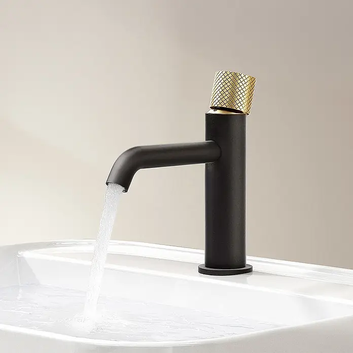 Emke Waschtischarmatur Griprill XF29 - Schwarz, Matt - Mattschwarzer Wasserhahn mit goldfarbenem strukturiertem Griff, der Wasser in ein weißes Waschbecken gießt.
