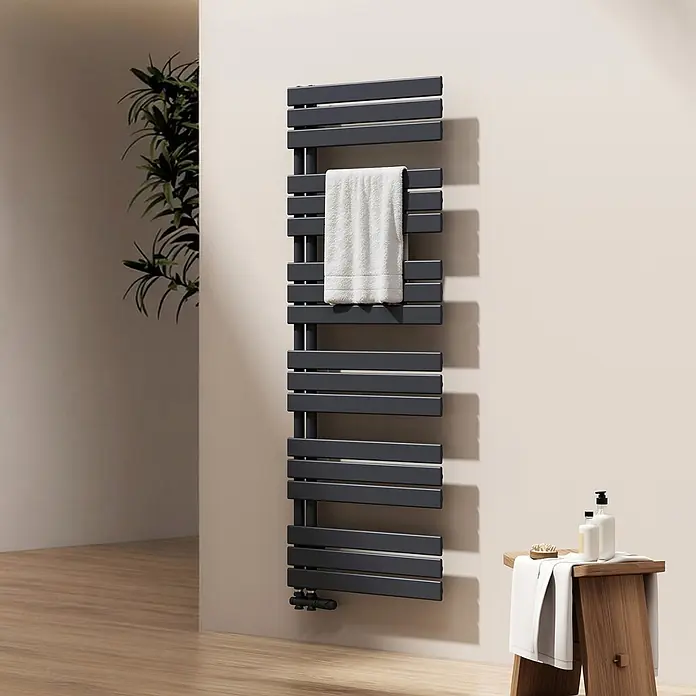 Emke Badheizkörper Flatrad SFTR1 - Anthrazit - Ein hoher, dunkelgrauer Anthrazit-Handtuchheizkörper an der Wand eines modernen Badezimmers, mit einem weißen Handtuch über einer seiner horizontalen Stangen.