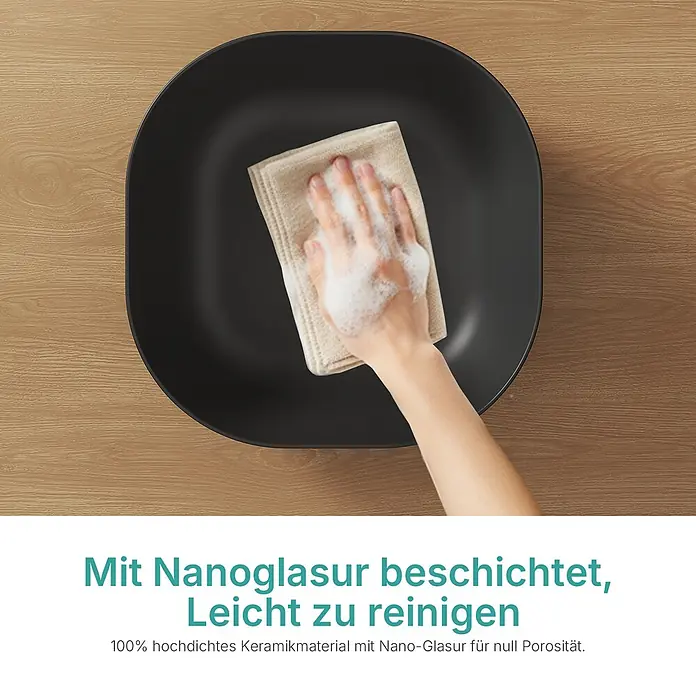 Emke Aufsatzwaschbecken Bovelari CB20 - 41,5 x 41,5 cm, Hahnloch: Ohne, Ohne Überlauf, Schwarz - Eine Hand reinigt ein schwarzes Keramikwaschbecken mit einem seifigen Tuch. Das Becken hat eine Nanoglasur für leichte Reinigung.