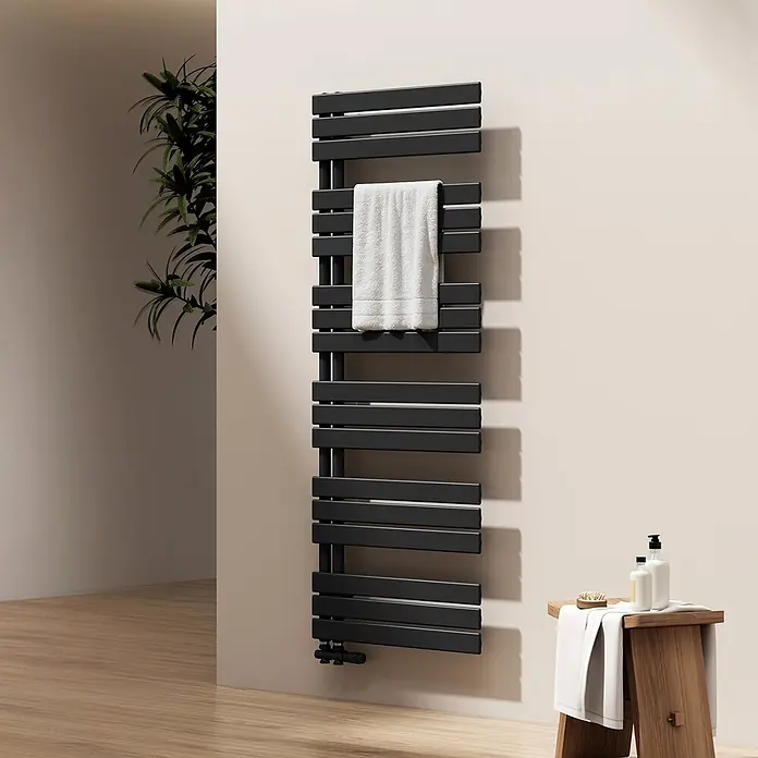 Emke Badheizkörper Flatrad SFTR1 - Schwarz - Schwarzer Flachpaneel-Handtuchheizkörper in einem modernen Bad, mit einem weißen Handtuch darauf. Ein Holzschemel mit Pflegeprodukten steht daneben.