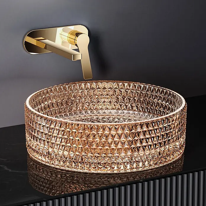 Emke Aufsatzwaschbecken Loviton CB18 - 36 x 36 cm, Hahnloch: Ohne, Ohne Überlauf, Roségold - Goldene Wandarmatur über einer runden, bernsteinfarbenen facettierten Glaswaschschale auf dunkler Arbeitsplatte.