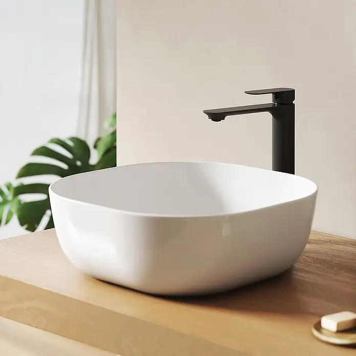 Emke Aufsatzwaschbecken Bovelari CB20 - 41,5 x 41,5 cm, Hahnloch: Ohne, Ohne Überlauf, Weiß - Weißes Keramik-Aufsatzwaschbecken mit schwarzem Wasserhahn auf einer Holzplatte im Badezimmer.