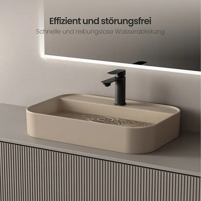 Emke Aufsatzwaschbecken Ceraform CB02 - 40 x 60 cm, Hahnloch: Mitte, Ohne Überlauf, Beige - Rechteckiges beiges Aufsatzwaschbecken mit schwarzem Wasserhahn auf grauem gerillten Waschtisch. Wasser kräuselt sich im Becken und reflektiert einen beleuchteten Spiegel.