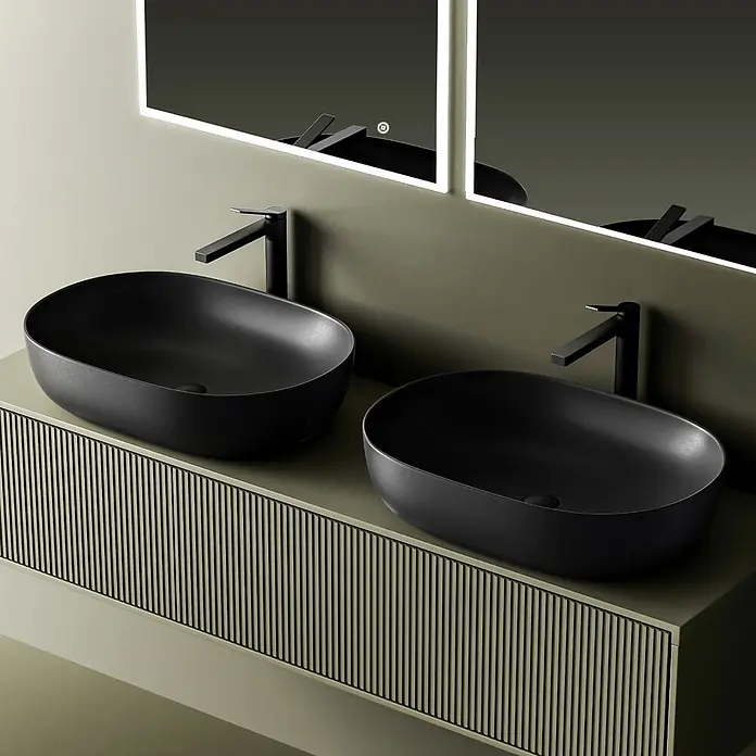 Emke Aufsatzwaschbecken Bovelari CB20 - Hahnloch: Ohne, Ohne Überlauf, Schwarz - Zwei matte schwarze ovale Aufsatzwaschbecken mit passenden Armaturen auf einem grünen gerippten Waschtisch unter beleuchteten Spiegeln.