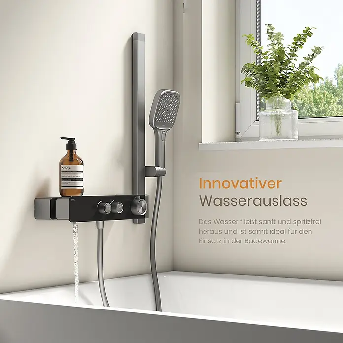 Emke Duschsystem SleeFlow F26 - Mit Thermostatarmatur, Lochabstand: 57,6 cm, Anzahl Strahlarten: 3 Stk., Anthrazit - Schwarze Duscharmatur mit Chromreglern und integriertem Auslauf lässt Wasser in eine Badewanne. Eine graue Handbrause ist daneben angebracht, neben einer Aesop-Flasche.