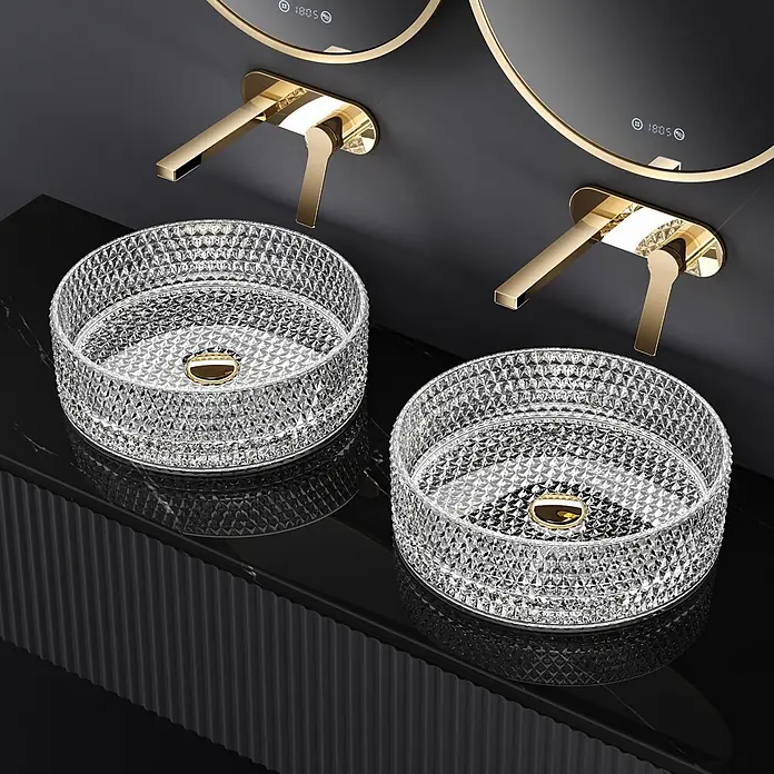 Emke Aufsatzwaschbecken Loviton CB18 - 36 x 36 cm, Hahnloch: Ohne, Ohne Überlauf, Transparent - Zwei klare, facettierte Glaswaschbecken mit goldenen Abläufen und passenden goldenen Wandarmaturen auf einem modernen schwarzen Waschtisch.