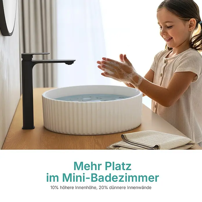 Emke Aufsatzwaschbecken Ceraround CB26 - Hahnloch: Ohne, Ohne Überlauf, Weiß - Ein Kind wäscht Hände in einem weißen geriffelten Aufsatzwaschbecken mit schwarzem Wasserhahn, das Becken spart Platz.