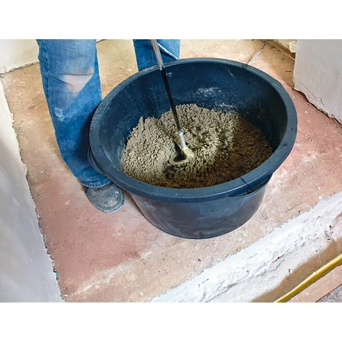 Quick-Mix Schnellestrich - 30 kg, Schichtdicke: 60 mm - Eine Person mischt mit einem Rührgerät Mörtel in einem großen schwarzen Eimer, um ihn für Bauarbeiten vorzubereiten.