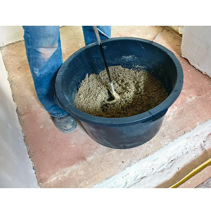 Quick-Mix Schnellestrich - 30 kg, Schichtdicke: 60 mm - Eine Person mischt mit einem Rührgerät Mörtel in einem großen schwarzen Eimer, um ihn für Bauarbeiten vorzubereiten.