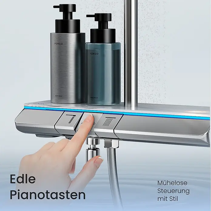 Emke Duschsystem Orbflow F25 - Mit Thermostatarmatur, Lochabstand: 110 cm, Anzahl Strahlarten: 3 Stk., Chrom - Eine Hand drückt einen Knopf auf einer modernen silbernen Duscharmatur mit Ablage für zwei Spenderflaschen, umgeben von Wassertropfen.