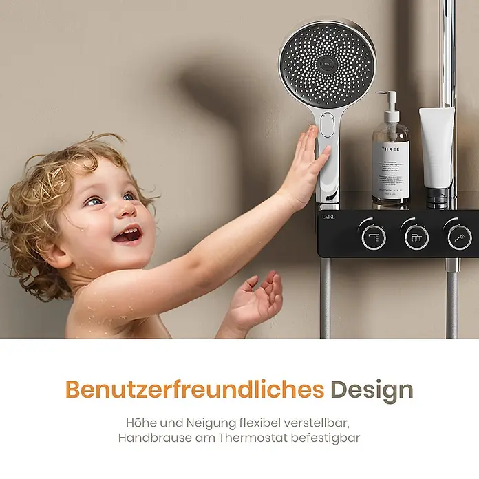 Emke Duschsystem SleeFlow F28 - Mit Thermostatarmatur, Lochabstand: 119 cm, Anzahl Strahlarten: 3 Stk., Chrom - Lächelndes Kind greift nach moderner silber-schwarzer Duscharmatur mit Bedienfeld und Ablage.