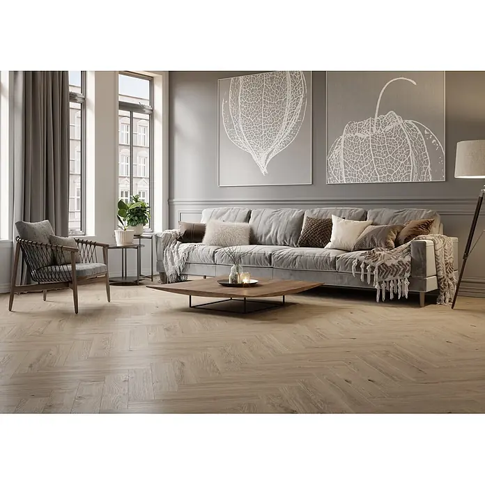 Krono Original Laminat Durastar Herringbone - Blonde Montanara Oak, Fischgrät, 630 x 126 x 9 mm - Modernes Wohnzimmer mit grauem Sofa, hellem Fischgrätparkett und eckigem Holztisch.