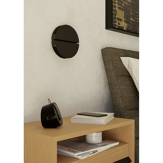 Eglo LED-Wandleuchte rund Pianosa - 5,3 W, Ø x H: 18 x 6 cm, Warmweiß - Schwarze runde Wandleuchte mit horizontaler Teilung, über einem Holznachttisch montiert.