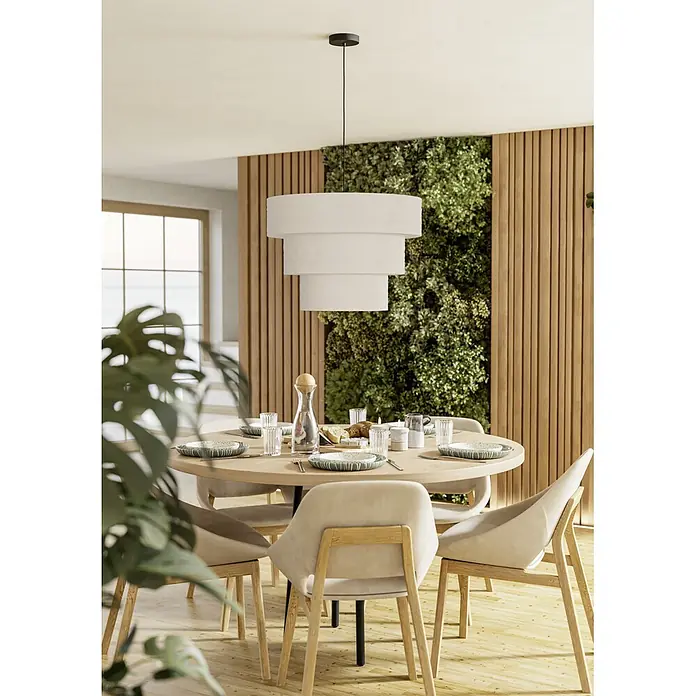Eglo Pendelleuchte rund - 25 W, Ø x H: 60 x 110 cm, Schwarz - Eine gestufte weiße Stoff-Pendelleuchte hängt über einem runden Esstisch aus Holz, gedeckt für eine Mahlzeit in einem hellen, modernen Esszimmer mit grüner Wand.
