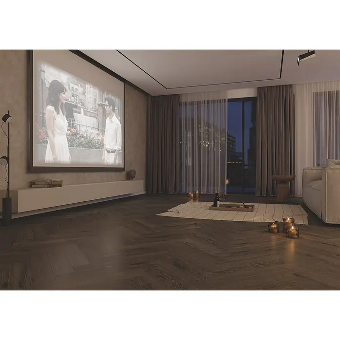 Krono Original Laminat Durastar Herringbone - Dark Montanara Oak, Fischgrät, 630 x 126 x 9 mm - Modernes Wohnzimmer mit Projektionsleinwand, dunklem Fischgrätparkett und gemütlicher Abendatmosphäre mit Bodensitzgelegenheit, Wein und Kerzen.