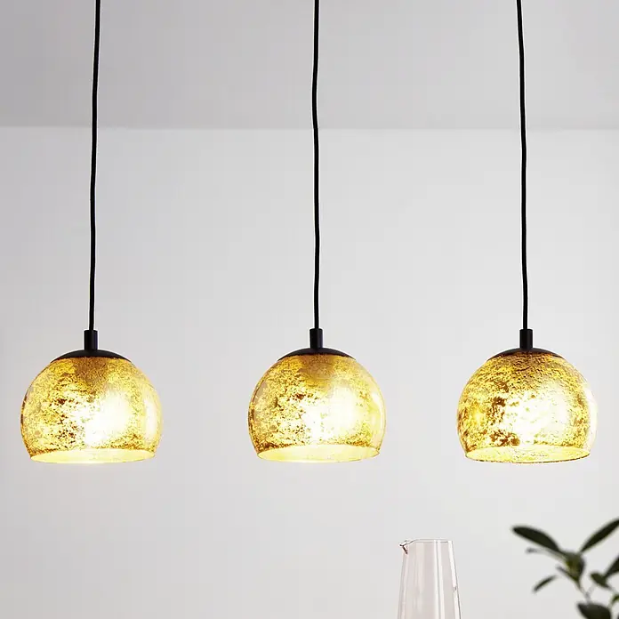 Eglo Pendelleuchte Albraccin - L x B x H: 78 x 19 x 110 cm, E27, Anzahl Leuchtmittel: 3 Stk. - Drei goldfarbene Pendelleuchten aus texturiertem Glas mit schwarzen Kabeln hängen von der Decke.