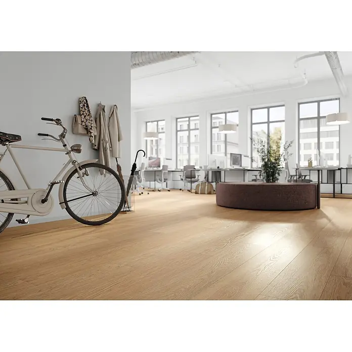 Krono Original Laminat Durastar - Natural Darcy Oak, Landhausdiele, 2.003 x 245 x 9 mm - Heller Holzboden, Sonnenlicht in einem modernen Büro mit Fahrrad und Sitzgelegenheiten reflektierend.
