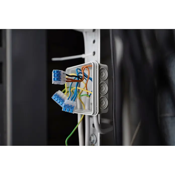 Ideal Hebelklemme 2/3/5-fach Gen II Kombipack - 30 Stk. - Offene Elektroabzweigdose mit bunten Kabeln, verbunden durch blaue Hebelklemmen.