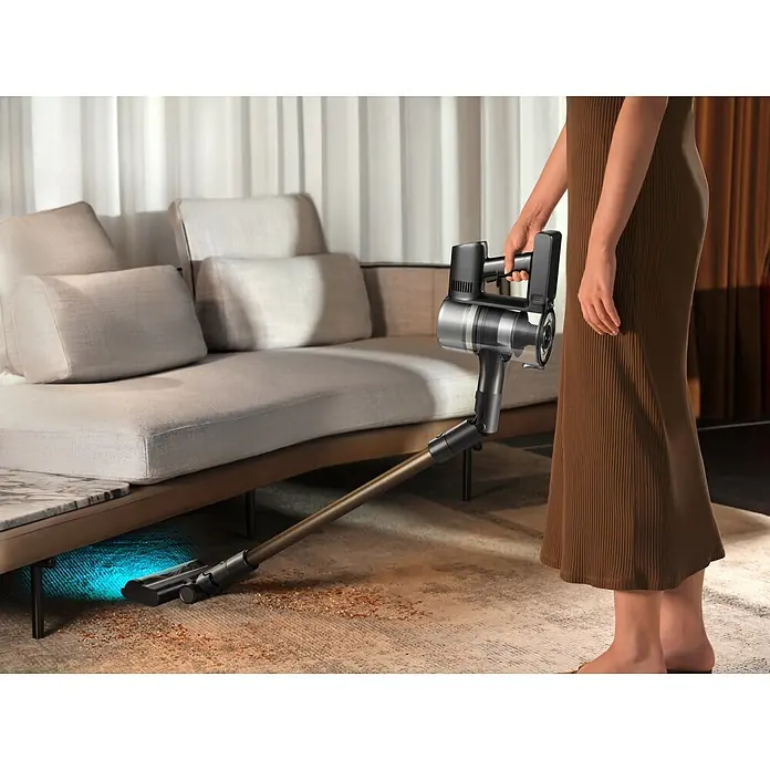 Mova Aspirador de batería S5 Sense - 570 W, Volumen de recipiente: 0,6 l - Aspiradora escoba sin cable con tubo flexible y cepillo iluminado limpiando bajo un sofá.