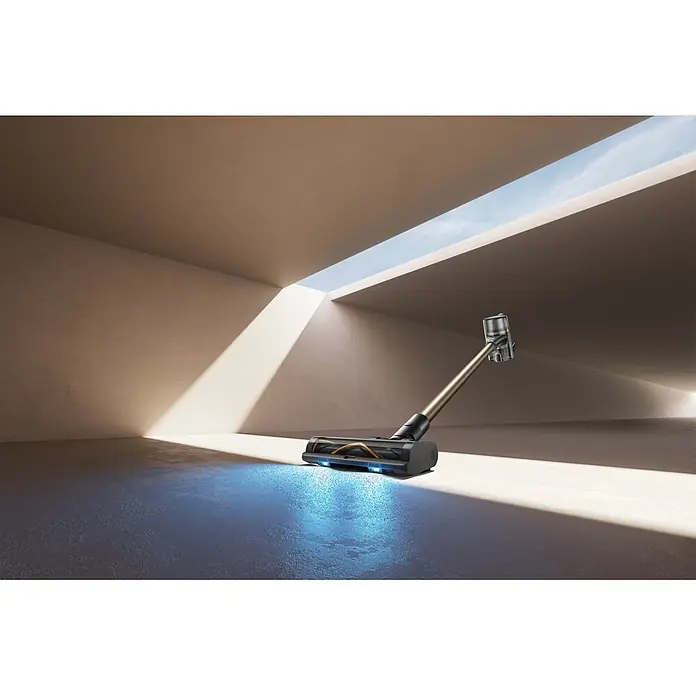 Mova Aspirador de batería S5 Sense - 570 W, Volumen de recipiente: 0,6 l - Aspirador escoba moderno dorado y negro con un cepillo iluminado en azul que revela el polvo en un suelo claro.