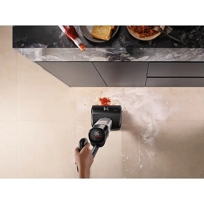 Mova Aspirador en seco y húmedo de batería X4 Pro - 450 W, Volumen de recipiente: 760 ml - Aspiradora de mano negra y gris limpiando salsa y harina derramadas en un suelo de cocina.