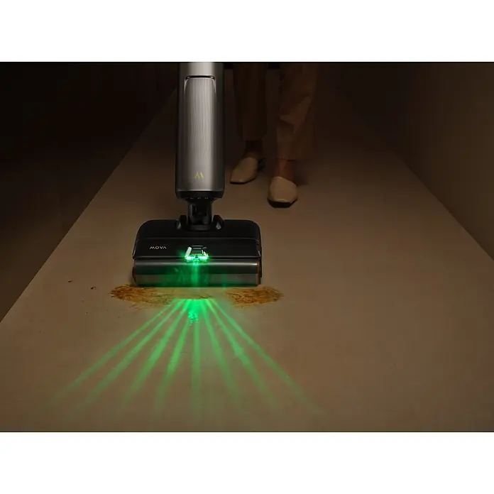 Mova Aspirador en seco y húmedo de batería X4 Pro - 450 W, Volumen de recipiente: 760 ml - Limpiador de suelos Mova gris oscuro con luces LED verdes iluminando un derrame en el suelo, usado por una persona.