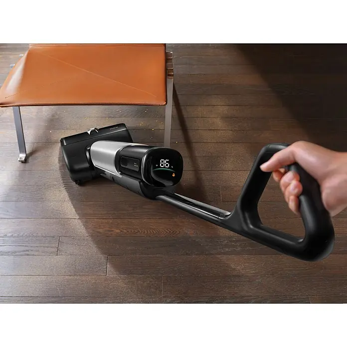 Mova Aspirador en seco y húmedo de batería X4 Pro - 450 W, Volumen de recipiente: 760 ml - Una persona usa una aspiradora VAOW negra y plateada para limpiar un suelo de madera bajo una silla. Su pantalla muestra 86%.