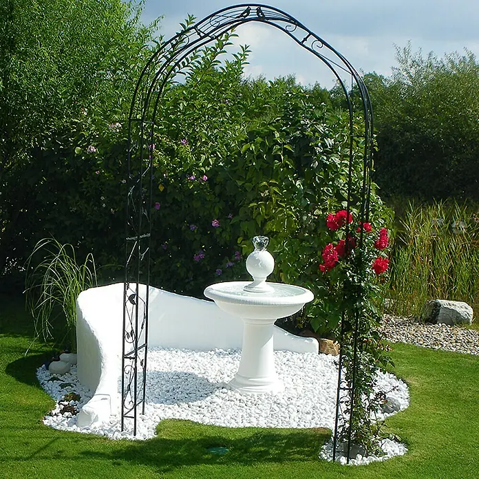 Min2C Marmorkiesel - Weiß, Körnung: 25 mm - 40 mm, 25 kg - Gartenarchitektur mit Rosenbogen, Brunnen und Sitzbank auf weißen Kieselsteinen, eingebettet in üppiges Grün.