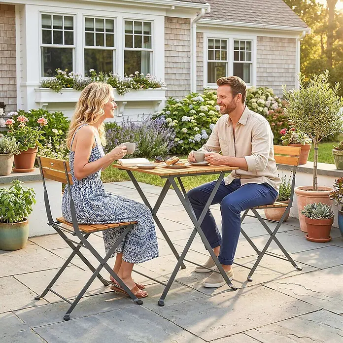 Outsunny Gartentisch-Set - Gesamtumfang: 3 -tlg., Stahl, Akazienholz, Klappbar - Ein Bistrotisch mit Holzlatten und zwei Klappstühle mit dunklen Metallrahmen, von einem Paar auf einer Terrasse genutzt.