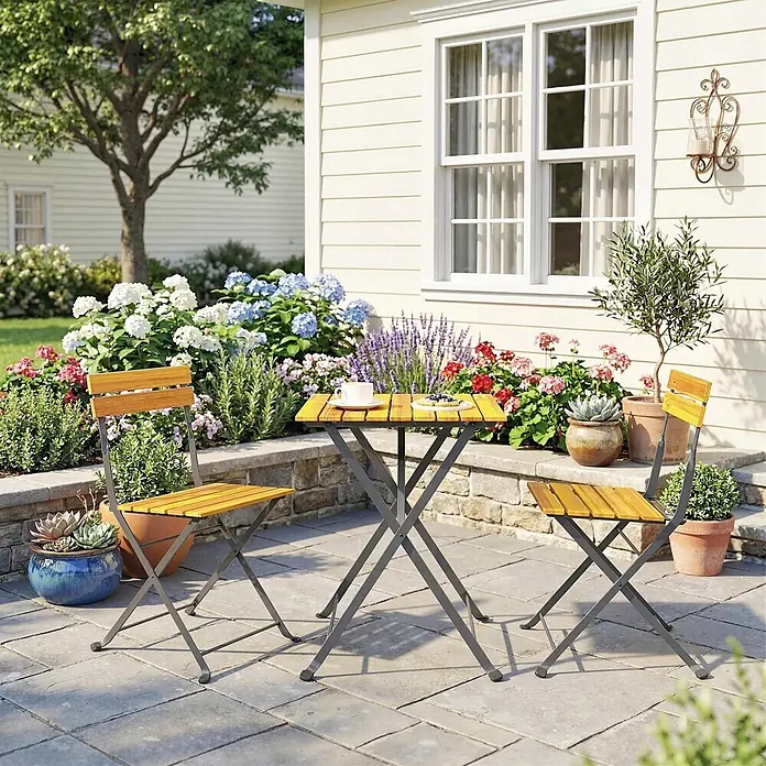 Outsunny Gartentisch-Set - Gesamtumfang: 3 -tlg., Stahl, Akazienholz, Klappbar - Holzlattentisch und zwei Stühle mit dunklen Metallrahmen auf einer Terrasse für draußen.