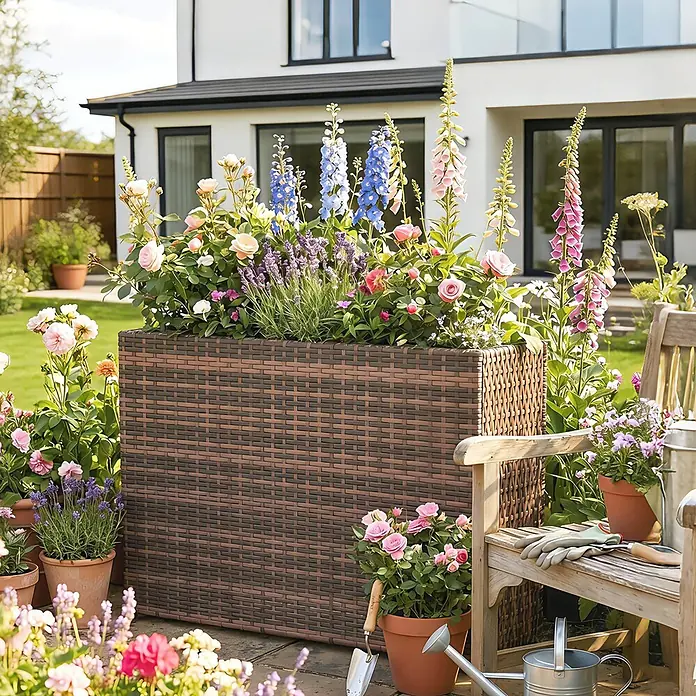 Outsunny Pflanzkasten - 1 Stk., Stahl, Braun - Großer brauner Pflanzkübel im Rattan-Stil, gefüllt mit bunten Blumen in einem Garten.