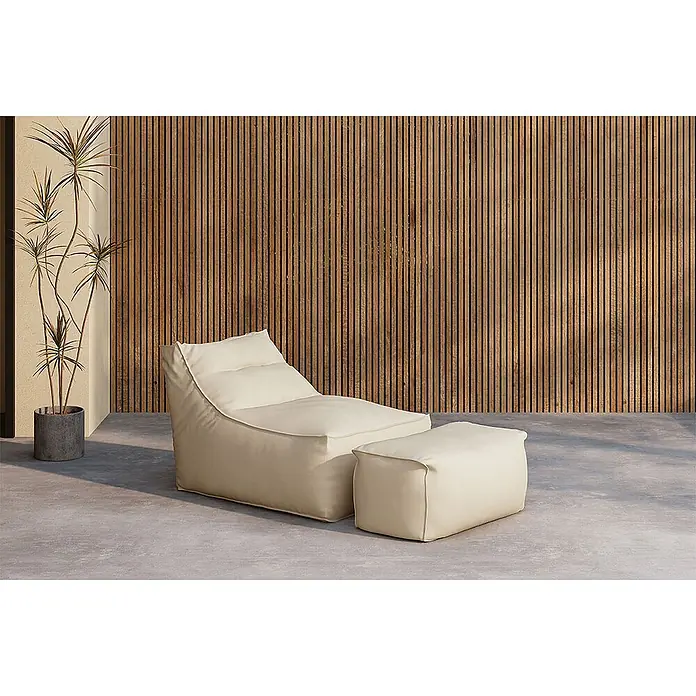 Ebuy24 Garten-Loungesessel Redang - 1 Stk., Polystyrol, Beige, B x T x H: 94 x 118 x 83 cm - Cremefarbener Sitzsack-Lounge-Sessel mit Hocker auf Betonboden, neben Pflanze und Holzlamellenwand.
