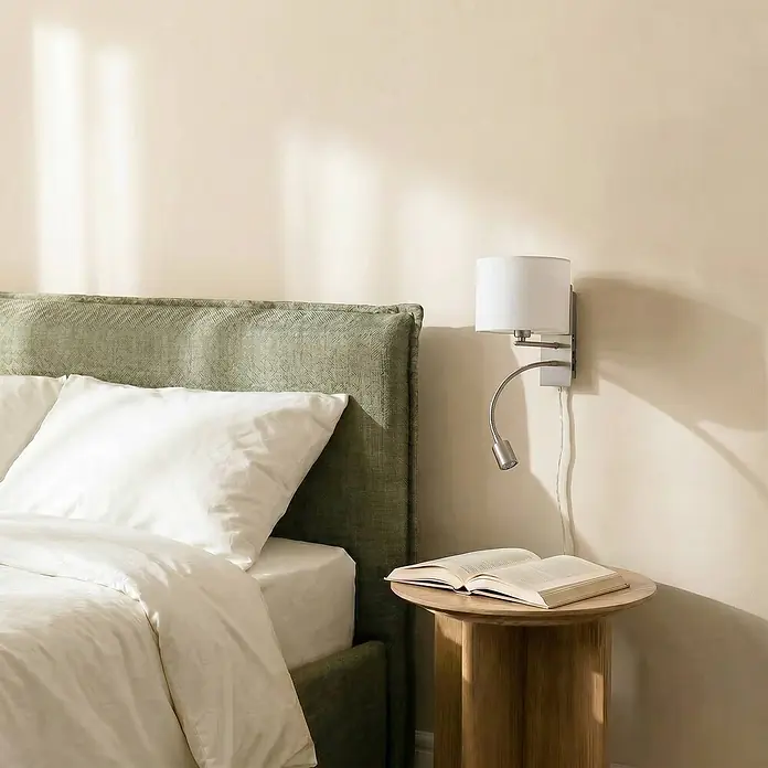 Lindby Wandleuchte Florens - L x B x H: 24 x 18 x 23,5 cm, alu / grau / zink, E14 - Bett mit grünem, strukturiertem Kopfteil und weißer Bettwäsche. Eine Metall-Wandleuchte mit Leselicht hängt über einem Holznachttisch mit Buch.