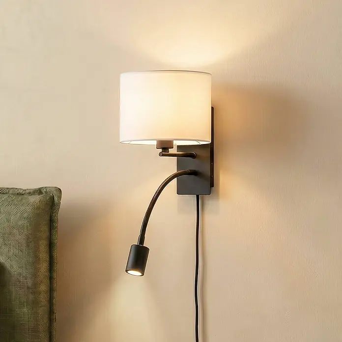 Lindby Wandleuchte Florens - weiß / opal, E14 - Schwarze Wandleuchte mit weißem Stoffschirm und flexiblem LED-Leselicht, neben einem Bett montiert.