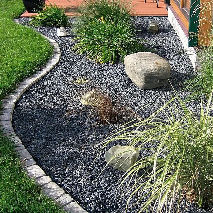 Min2C Marmorkiesel - Schwarz, Körnung: 15 mm - 25 mm, 25 kg - Gartengestaltung mit dunklem Ziersplitt, Steinen und Gräsern. Der Splitt bildet eine moderne und pflegeleichte Beetumrandung.