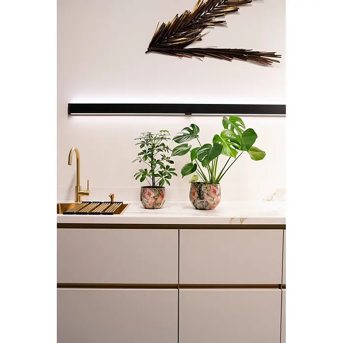 Ter Steege Übertopf rund Monstera Mystery - Ø x H: 30 x 28 cm, Metall, Grün - Moderne Küche mit hellen Schränken, goldenen Griffen und passender Armatur, dazu Pflanzen auf einer Marmor-Look-Arbeitsplatte unter LED-Beleuchtung.