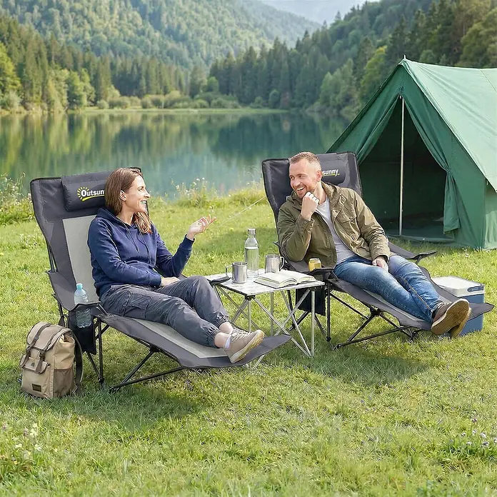 Outsunny Campingstuhl - 2 Stk., Metall, 600D Oxford-Stoff, Schaumstoff, Klappbar, Dunkelgrau - Zwei graue Outsunny Campingstühle mit Kopfstützen und ein silberner Klapptisch, von einem Paar zur Entspannung im Freien genutzt.