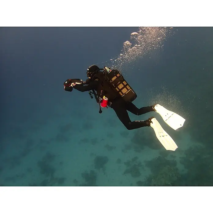 Sublue Tauchscooter Navbow 2026 - L x B x H: 486 x 327 x 177 mm - Taucher im schwarzen Neoprenanzug mit weißen Flossen, hält Unterwasserkamera im klaren blauen Wasser.