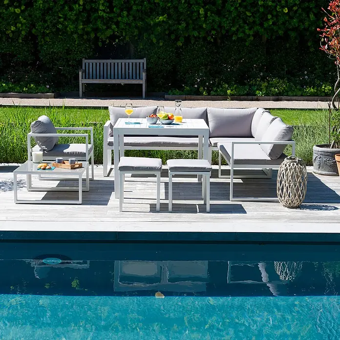 Happy Garden Loungemöbel-Set IBIZA - 6 -tlg., Aluminium, Grau - Weißes Outdoor-Lounge-Set mit grauen Kissen auf Holzterrasse am Pool, für eine Mahlzeit arrangiert.