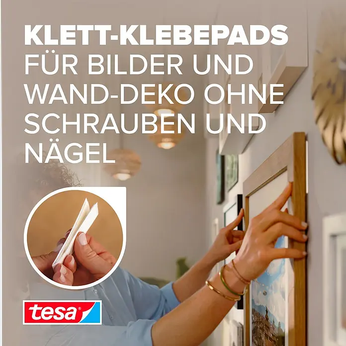 Tesa Selbstklebestrip POWERSTRIPS CLICK 4X2 L - 4 Stk., B x L: 20 x 85 mm - Weiße tesa Klett-Klebepads zum Aufhängen eines Bilderrahmens an der Wand. Nahaufnahme zeigt Hände mit den Pads.