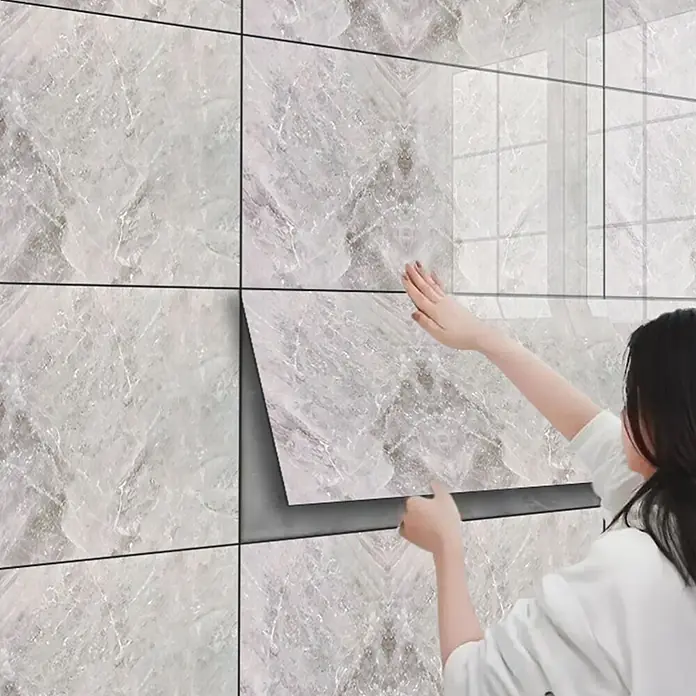 Panel de pared Mármol - 60 x 30 cm, Gris, 2 ud. - Persona aplicando azulejos de pared autoadhesivos efecto mármol gris.