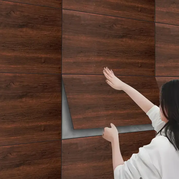 Panel de pared Madera - 60 x 30 cm, Madera oscura, 2 ud. - Paneles de pared autoadhesivos de madera oscura se aplican a una pared con la mano, mostrando el reverso adhesivo.