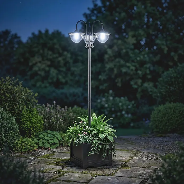 Outsunny Solar-Stehleuchte - 1,92 W, Schwarz - Schwarze Gartenlaterne mit zwei Leuchten und integriertem Pflanzenkübel voller Pflanzen, die einen Gartenweg nachts beleuchtet.