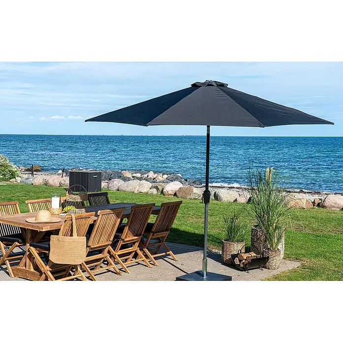 Tinkaro Marktschirm - dunkelgrau - Eine hölzerne Outdoor-Essgruppe mit schwarzem Sonnenschirm auf einer Terrasse am Meer.