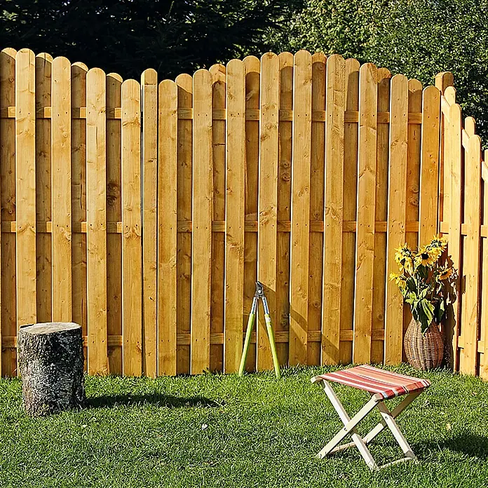 Sichtschutzelement Starnberg - 90 x 100/180 cm, Abgeschrägt, Herbstgold - Gartenszene mit Holzzaun, Baumstumpf, Gartenschere, Hocker und Sonnenblumen in einem Korb. Der Zaun ist aus hellbraunem Holz gefertigt.