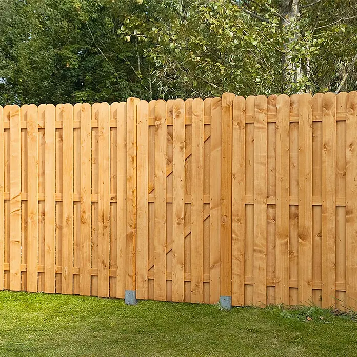 Gartentor Starnberg90 x 180 cm, Herbstgold - Nahaufnahme eines Palisadenzauns aus Holz, der einen Garten umgibt. Der Zaun ist hellbraun und erstreckt sich vor Bäumen und Grünflächen.