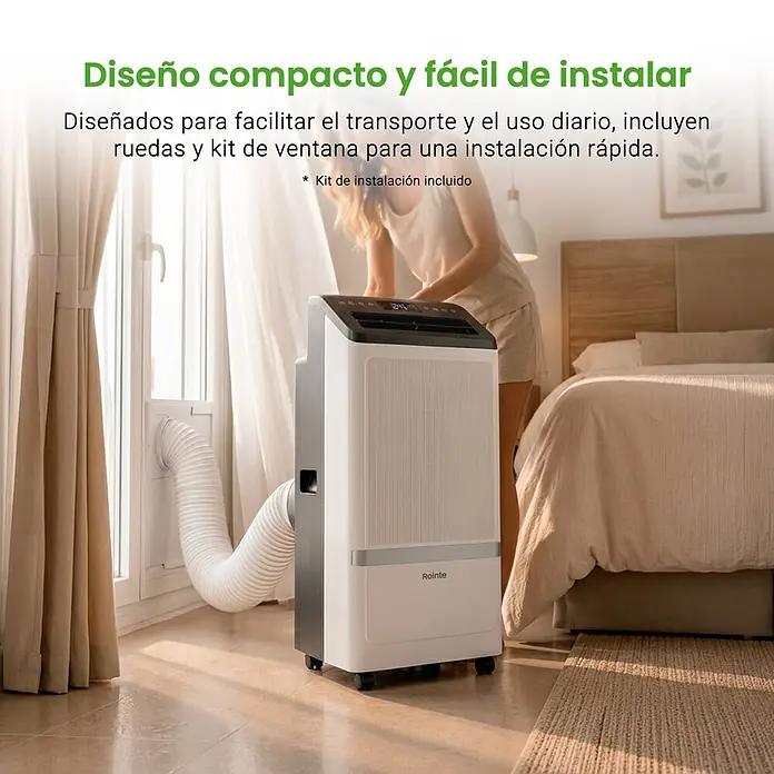 Rointe Aire acondicionado portátil Alghero 3000 - 3.000 W, Tamaño de la estancia: 20 m² - 30 m², Blanco - Aire acondicionado portátil blanco y gris con ruedas, manguera de escape conectada a una ventana, en un dormitorio.