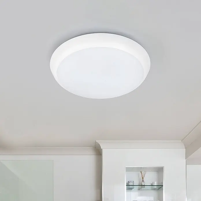 Arcchio Deckenleuchte Augustin - weiß / opal, weiß / opal - Eine weiße, runde LED-Deckenleuchte ist bündig an einer hellgrauen Decke in einem modernen Raum montiert.