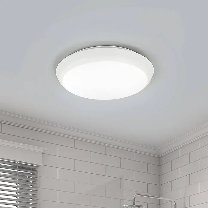 Arcchio Deckenleuchte Augustin - weiß / opal, weiß / opal - Eine weiße, runde LED-Deckenleuchte mit mattierter Abdeckung beleuchtet ein modernes Badezimmer mit weißen Fliesen und einer Dusche.