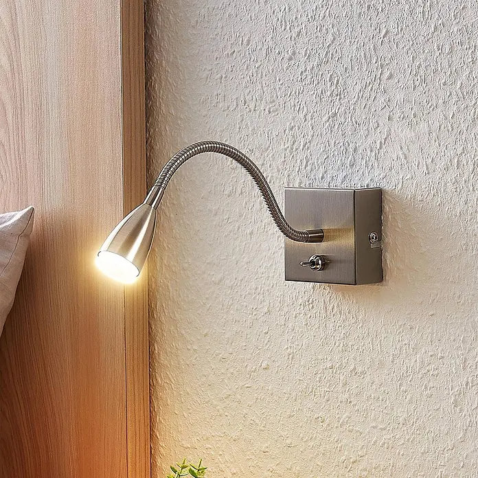 Lindby Wandleuchte Jolka - L x B x H: 30 x 7 x 7 cm, alu / grau / zink, alu / grau / zink - Wandleuchte aus gebürstetem Metall mit flexiblem Schwanenhals und Kippschalter, neben Holz-Kopfteil montiert, Licht an.